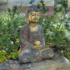A hand-carved dark limestone Buddha statue with a painted finish, seated 