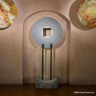 Gallery-worthy sculpture, ancient/contemporary. The hand-carved blue-gray granite pendant features a ribbed pattern on both surfaces and can be used indoors or outdoors, supported by an iron stand.