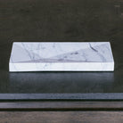 A rectangular Carrara marble bath tray with visible white and gray patterns characteristic of marble stone.