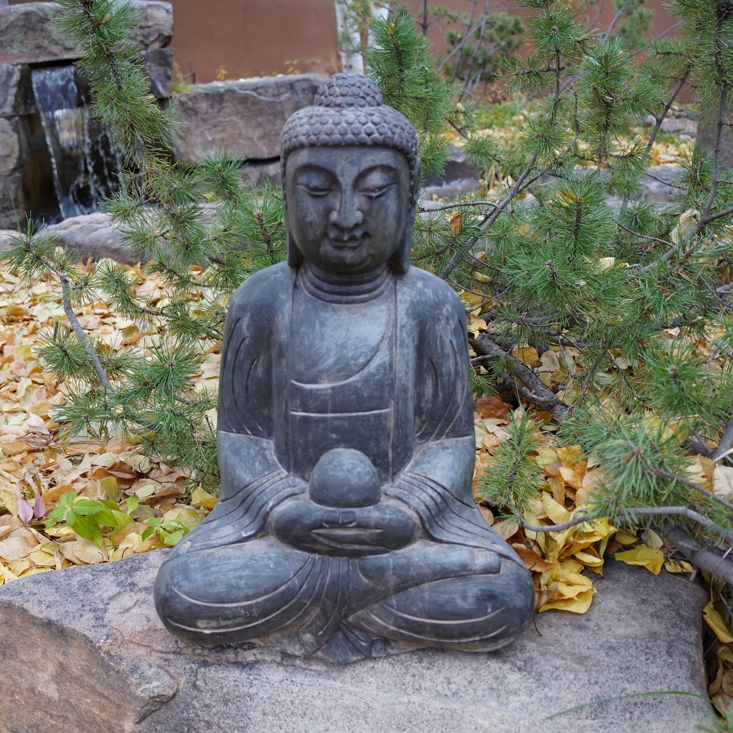 A hand-carved dark limestone Buddha statue seated 