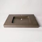A contemporary bath vanity with an integral sink carved from a solid block of noce basalt. It has a center-hole faucet drilling.