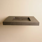 A contemporary bath vanity with an integral sink carved from a solid block of noce basalt. It has a center-hole faucet drilling.