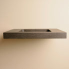 A contemporary bath vanity with an integral sink carved from a solid block of noce basalt. It has a center-hole faucet drilling.