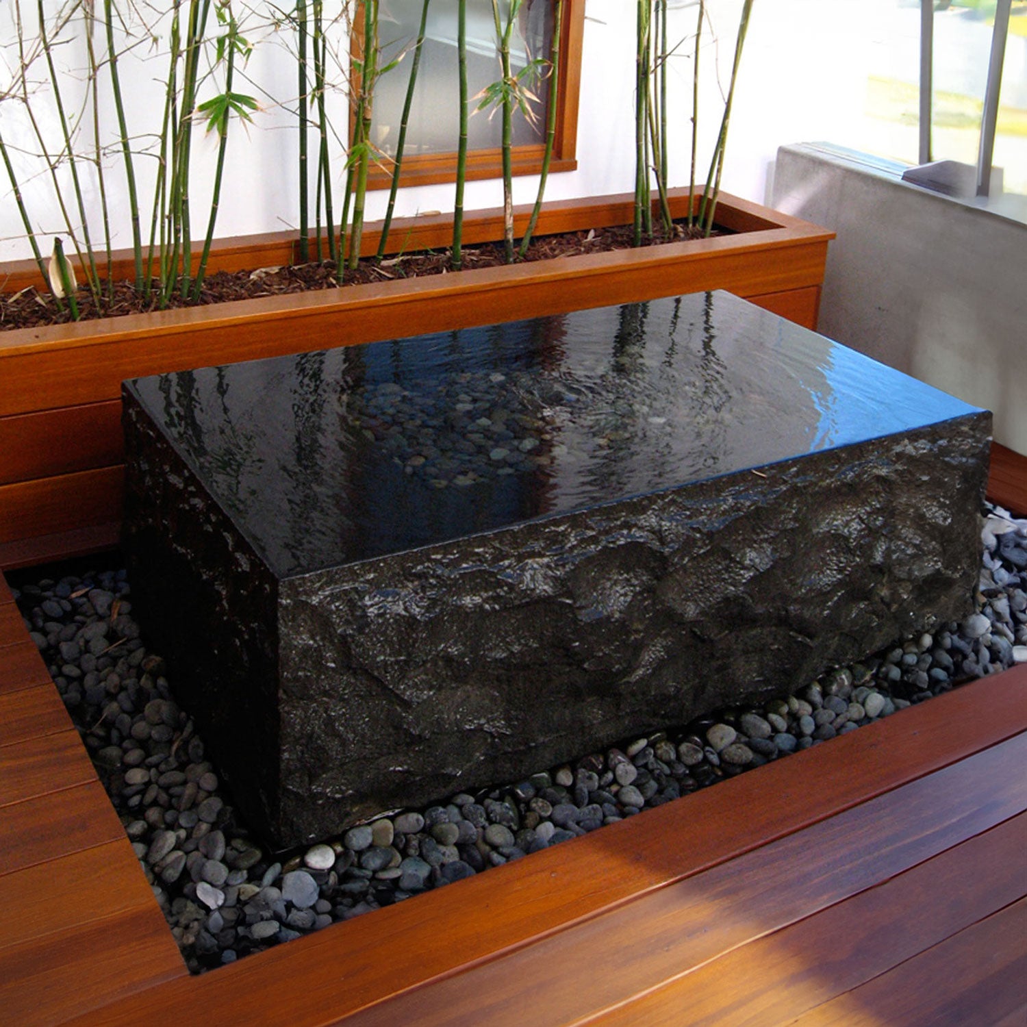 A rectangular black granite fountain with rough chiseled exterior and polished top