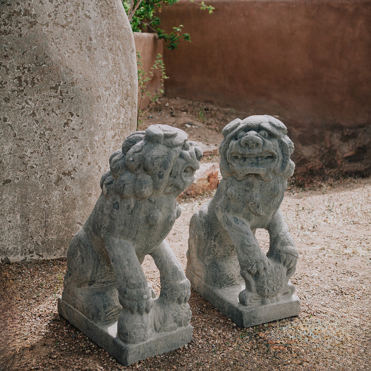 pair of antique stone lions were hand-sculpted from a block of dark limestone. They are also known as lion dogs or foo dogs/fu dogs.