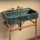 Fluted Lumbre Bath Sink carved from Verde Indio Marble on top of an Aged Brass  Elemental  Facet Crossbar Stand