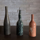 Three marble bottle forms are hand-carved from different types of stone.