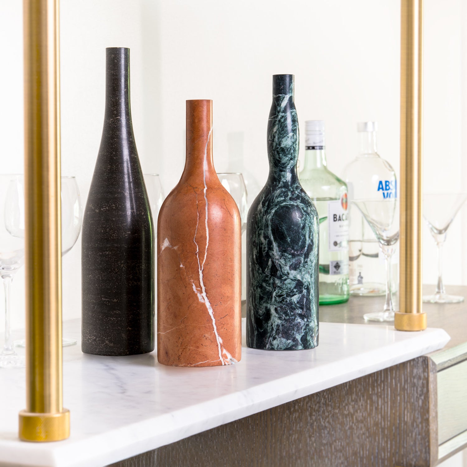 Three marble bottle forms are hand-carved from different types of stone.