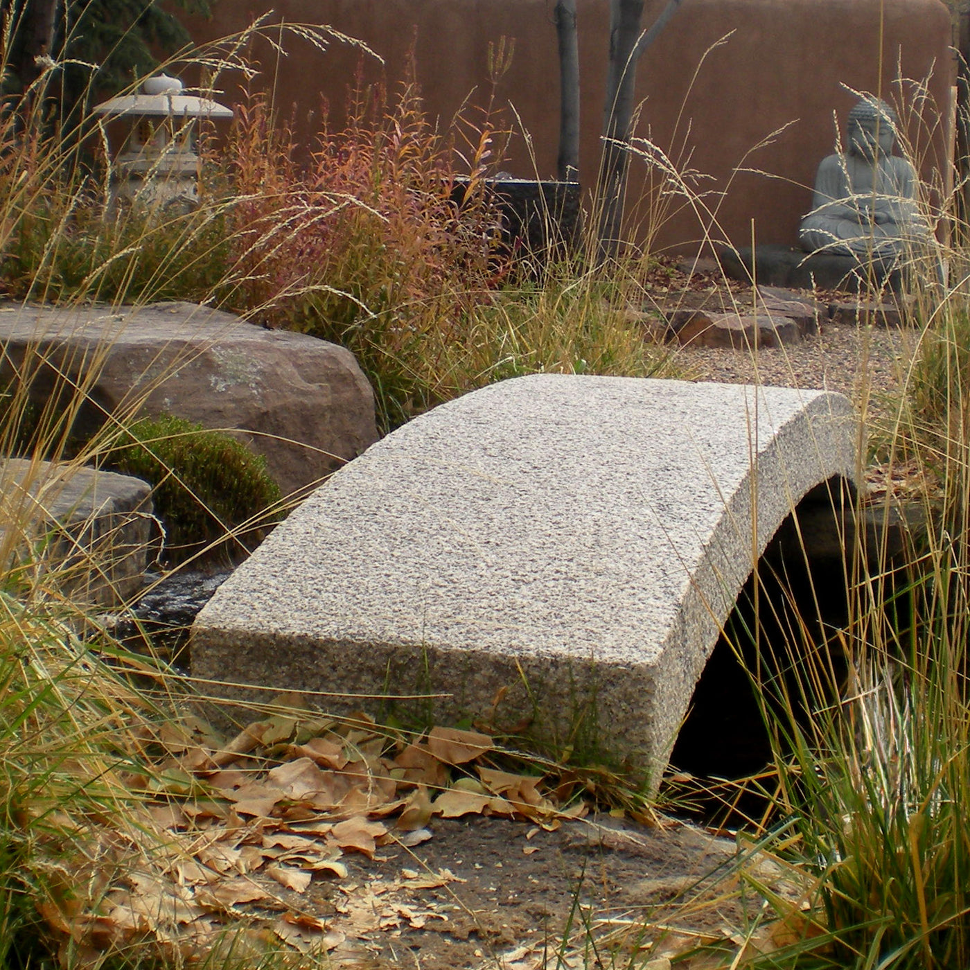 Granite bridge in a garden setting with grass and rocks