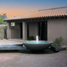 A contemporary style custom fountain with a large granite stone placed on a patio.