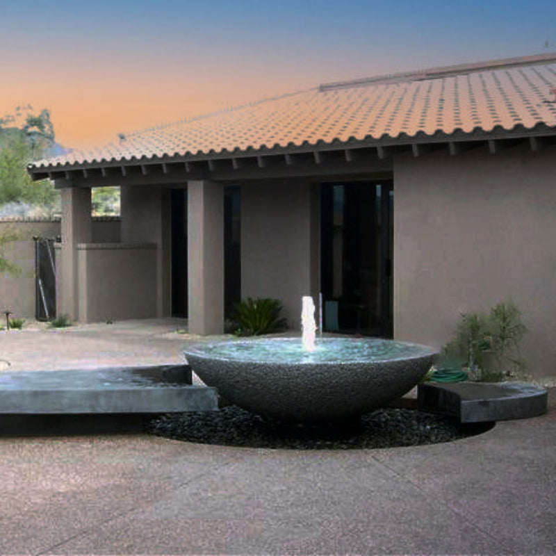 A contemporary style custom fountain with a large granite stone placed on a patio.