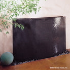A polished, slightly curved blue gray granite waterwall fountain with water sheets over the face.