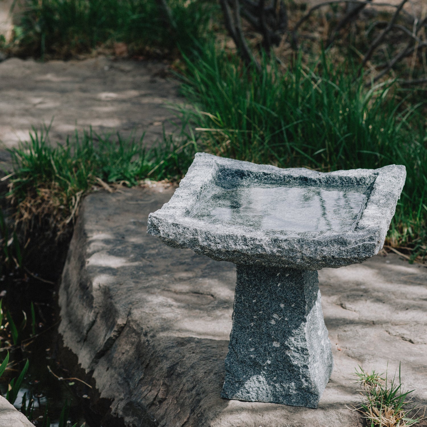 This birdbath is hand-carved from blue-gray granite with a rough chiseled finish