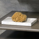 A rectangular Carrara marble bath tray with visible white and gray patterns characteristic of marble stone.