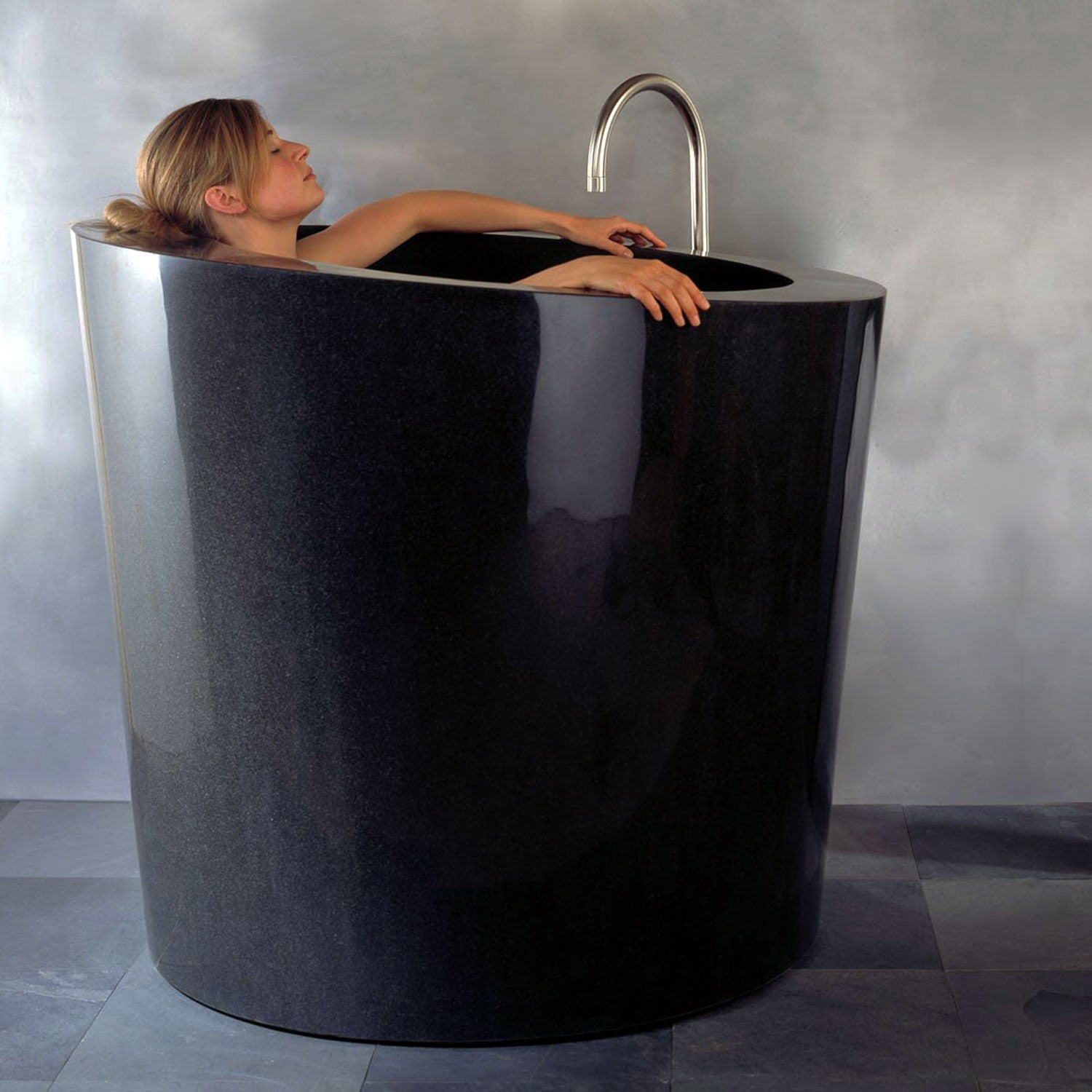 The Stone Forest Oval Soaking Tub is carved in a monumental block of black granite with a polished finish. This Bathtub is made on a custom basis only.