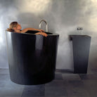 The Stone Forest Oval Soaking Tub is carved in a monumental block of black granite with a polished finish. This Bathtub is made on a custom basis only.