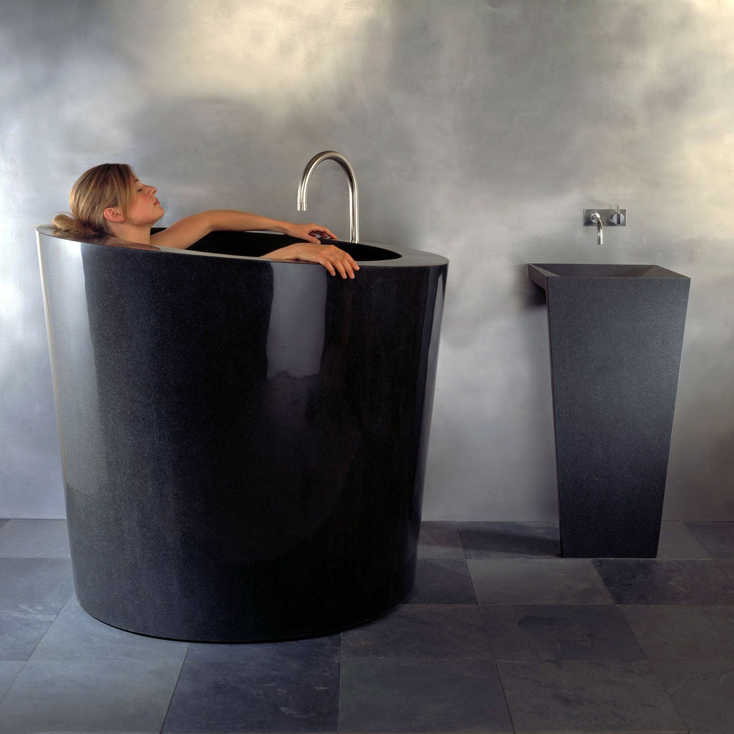 The Stone Forest Oval Soaking Tub is carved in a monumental block of black granite with a polished finish. This Bathtub is made on a custom basis only.