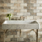 A honed carrara marble trough sink paired with polished nickel elemental classic trough vanity legs