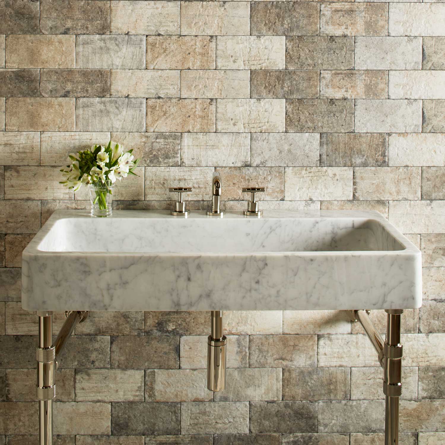 A honed carrara marble trough sink paired with polished nickel elemental classic trough vanity legs