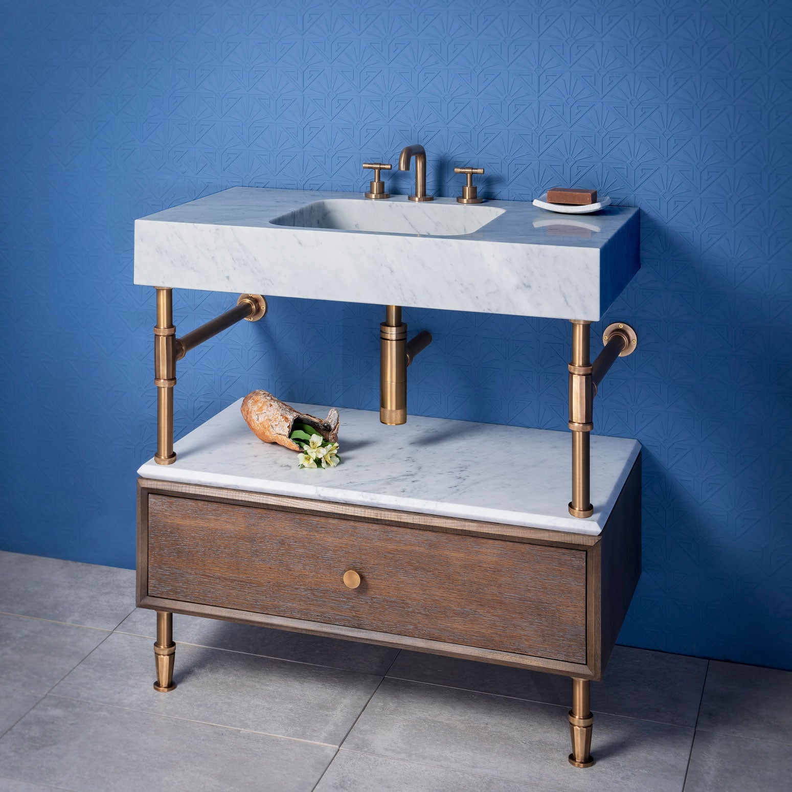 The Terra Bath Sink is carved from a solid block of carrara marble. Featuring a honed finish. Shown here on Elemental Facet Drawer Vanity in aged brass with a 10"H cement gray wood drawer with a carrara shelf cap.&nbsp;