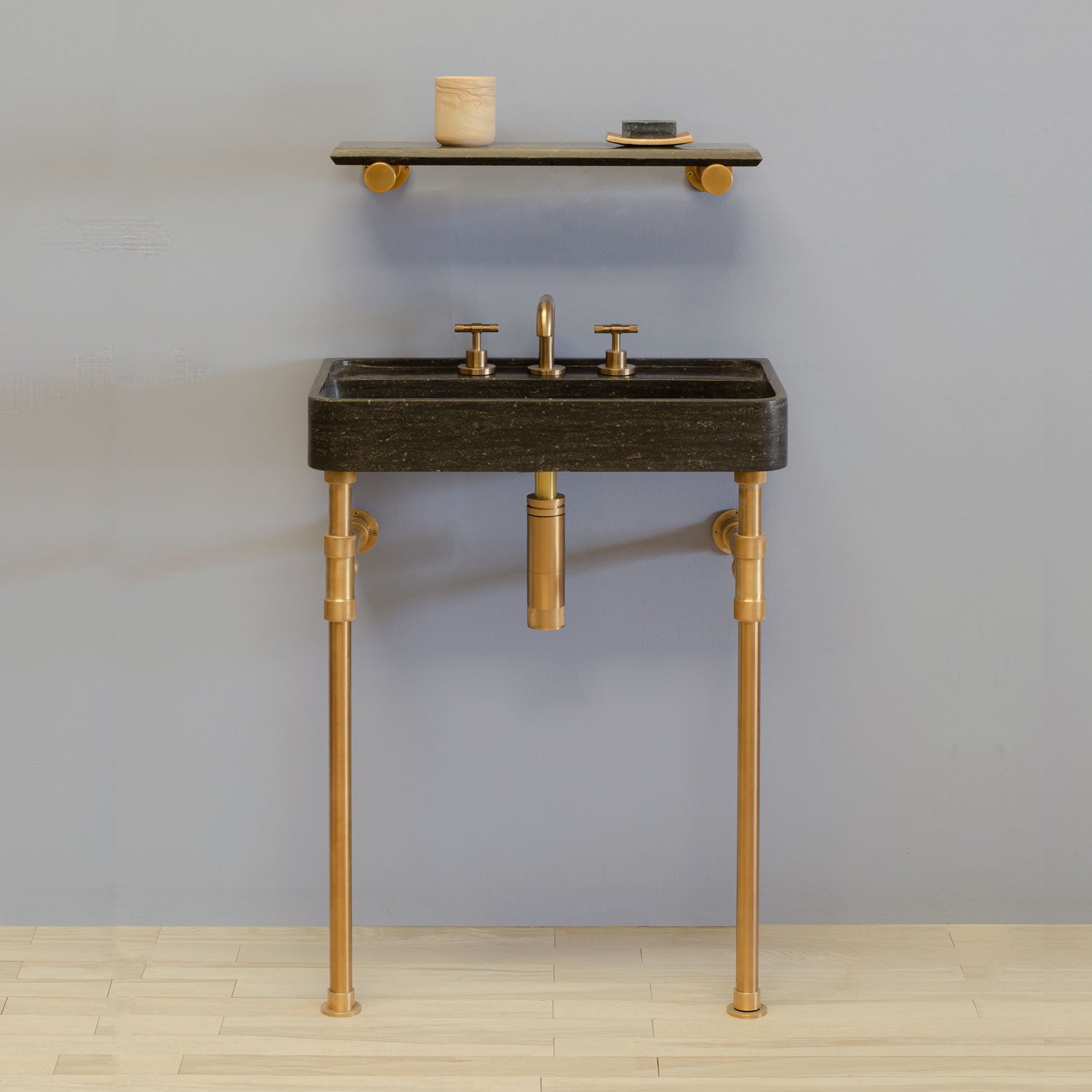 Antique gray limestone Lumbre bath sink, mounted on aged brass vanity legs with accessory shelf